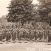 <p>Taken in the spring of 1942, this photo postcard may show the combat platoon organized early in the Second World War to protect Fort Slocum from saboteurs and commandos.&#160; The men stand south of Buildings 61 (left) and 59-60 (right).&#160; With equipment spanning 30-plus years of Army designs—from 1903 Springfield rifles through 1917 Brodie helmets and water-cooled machine guns (on carts) to 1930s uniforms—the platoon embodies the American soldier in transition from doughboy to GI.</p>